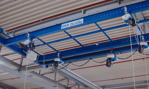 Blauer Brückenkran mit 1,5 Tonnen Tragkraft unter Hallendach, vier Seilzüge für flexiblen Lasttransport montiert.